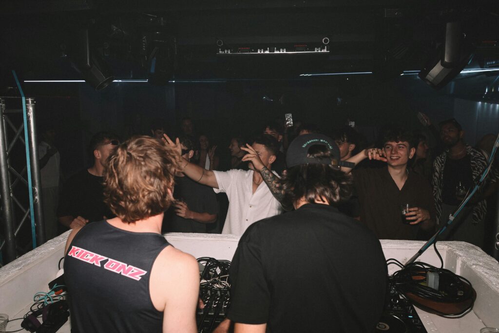 A dynamic scene of a DJ performing at a vibrant night club with an excited crowd.