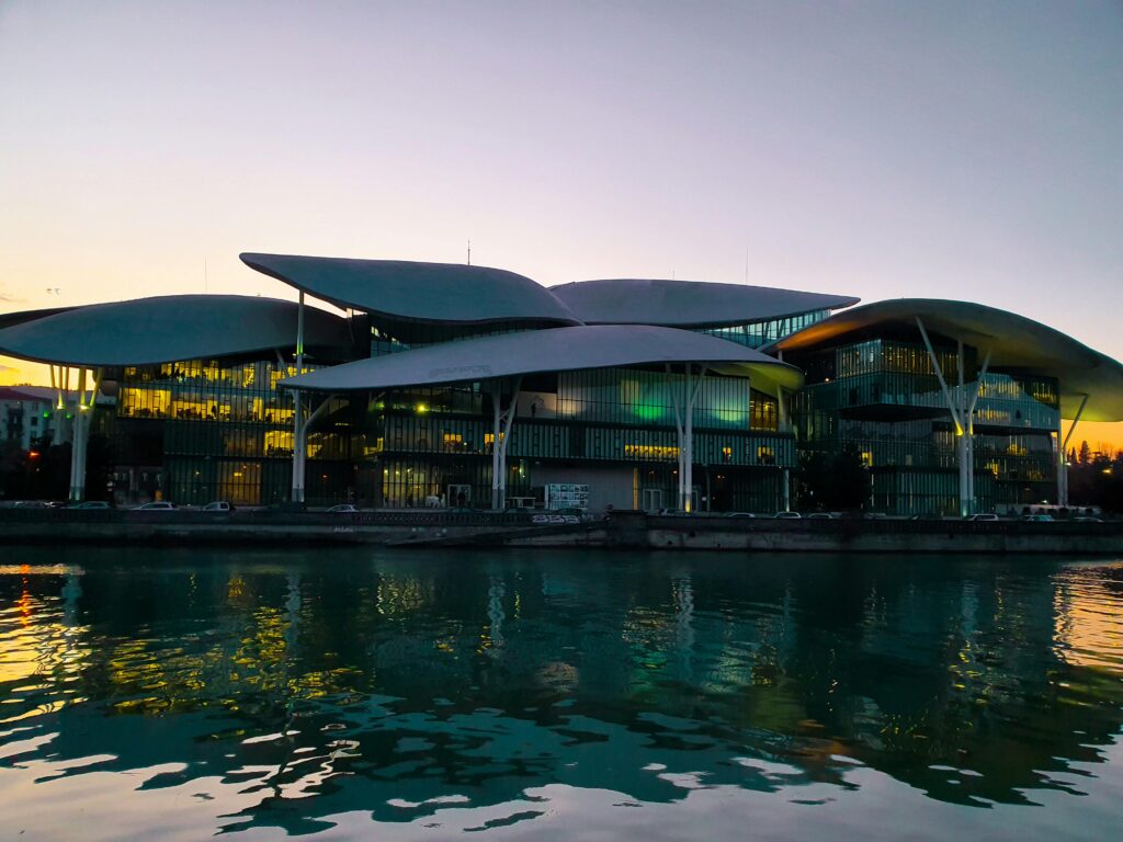 Stunning image of the Tbilisi Public Service Hall reflecting on water during twilight.